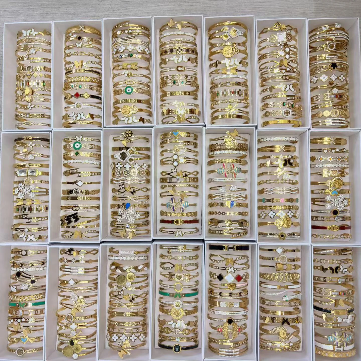 Gold-toned bracelets and bangles with decorative motifs arranged in white trays