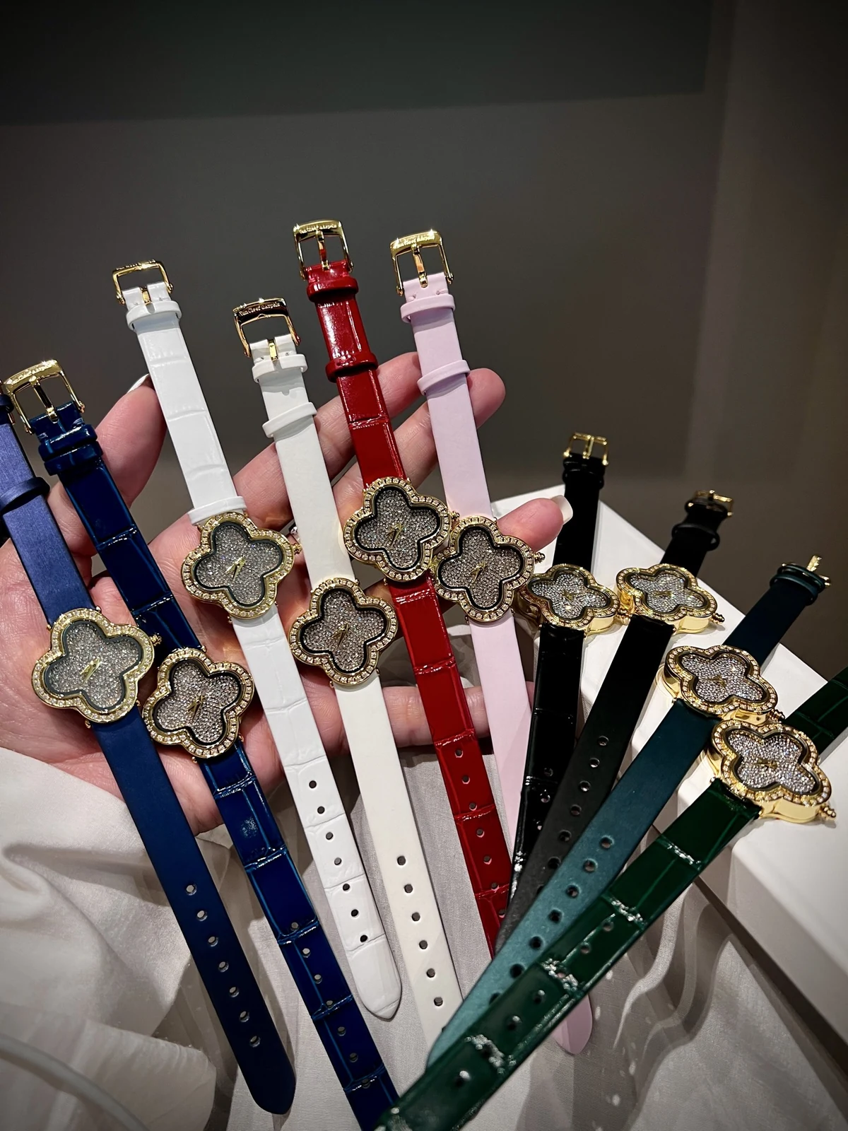 Flower-shaped watches with colorful straps displayed across a hand